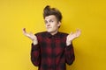 Uncertain guy shrugs on a yellow isolated background, hipster with a funny hairstyle does not understand Royalty Free Stock Photo