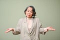 Uncertain 60s aged asian woman shrugging her shoulders. depends on you, I don`t care gesture Royalty Free Stock Photo