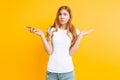 Uncertain woman with a phone in her hands, depicts misunderstanding and uncertainty on a yellow background