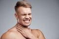 This is so uncomfortable. Studio shot of a muscular young man experiencing neck pain against a grey background. Royalty Free Stock Photo