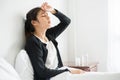 An uncomfortable woman sits on the bed and has medicine on the table