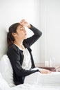 An uncomfortable woman sits on the bed and has medicine on the table