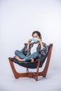 An uncomfortable woman sitting on a chair and wearing a mask