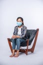 An uncomfortable woman sitting on a chair and wearing a mask