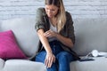 Uncomfortable young woman scratching her arm while sitting on the sofa at home Royalty Free Stock Photo