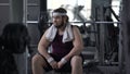 Unconfident chubby man in gym feeling upset because of excess weight, shyness