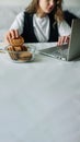 Unconscious eating. Bad habits. Selective focus of hand of concentrated female working on laptop at the kitchen table Royalty Free Stock Photo