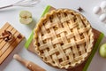 Uncooked apple pie into a baking dish ready for cooking on a white table surrounded by ingredients