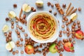 Uncooked apple tart in the baking dish decorated with fresh sliced apples, hazelnuts, cinnamon sticks, anise stars. Homemade pie