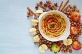 Uncooked apple tart in the baking dish decorated with fresh sliced apples, hazelnuts, cinnamon sticks, anise stars. Vegetarian pie