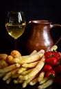 Uncooked asparagus, potatos and strawberries in front of a black background, with a glass of wine and a jar like a stil