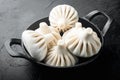 Uncooked Baozi chinese dumplings. Azian dumplings, in frying cast iron pan, on black stone background