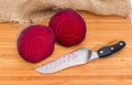 Uncooked beetroot cut in half and knife on cutting board Royalty Free Stock Photo