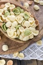 Uncooked colorful orecchiette in a wooden bowl.