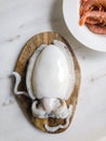 Uncooked Cuttlefish on wooden cutting board, shrimps in white ceramic plate - fresh seafood from above Royalty Free Stock Photo