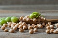 Uncooked dried chickpeas in wooden spoon with raw green chickpea pod plant on wooden table