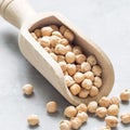 Uncooked dry chickpeas in wooden scoop, closeup, square