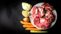 Uncooked food. Raw beef bones, and vegetables on black background. Ingredients for making beef broth Royalty Free Stock Photo