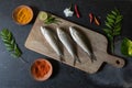 Uncooked fresh fish on a wooden board along with spice condiments with use of selective focus. Royalty Free Stock Photo