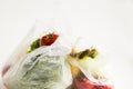 Uncooked,fresh vegetables and fruits in plastic shopping bags on white background with copy space. Royalty Free Stock Photo