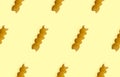 Uncooked fusilli pasta isolated on yellow seamless pattern. Itallian spiral pasta close-up on orange seamless background