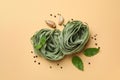 Uncooked green pasta and spices on beige background