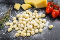 Uncooked homemade potato gnocchi with ingredients for cooking pasta. Black background. Top view