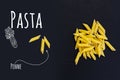 Uncooked Italian pasta Penne on black slate stone background