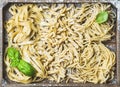 Uncooked Italian pasta in wooden tray with basil and flour Royalty Free Stock Photo