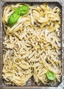 Uncooked Italian pasta in wooden tray with basil and flour Royalty Free Stock Photo