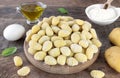 Uncooked italian potato gnocchi and cooking ingredients on wooden background.