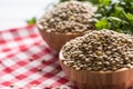 Uncooked lentils in wooden bowles with parsley herbs on kitchen table