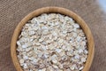 Uncooked oatmeal or oat flakes in wooden bowl on rustic background Royalty Free Stock Photo