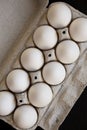 Uncooked Organic White Eggs in a paper box on a black background, overhead view. Flat lay, top view, from above Royalty Free Stock Photo