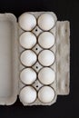 Uncooked Organic White Eggs in a paper box on a black surface, top view. Flat lay, overhead, from above Royalty Free Stock Photo