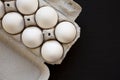 Uncooked Organic White Eggs in a paper box on a black surface, top view. Flat lay, overhead, from above. Copy space Royalty Free Stock Photo