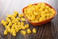 Raw pasta lumache in bowl, scattered pasta on wooden table