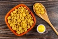 Uncooked pasta lumache in bowl, pasta in spoon, salt on table. Top view