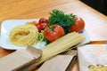 Uncooked pasta noodles inside a paper packaging with fresh tomatoes and celery. Fresh spaghetti ingredients Royalty Free Stock Photo