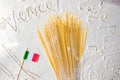 Uncooked pasta spaghetti and italian flag close-up on floured white background. Travelling to Italy back concept