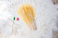 Uncooked pasta spaghetti macaroni and italian flag on floured table. Words Venice, Rome and Pasta written in flour