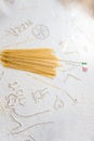 Uncooked pasta spaghetti macaroni and italian flag on floured white background. Food travel italian cuisine concept