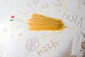 Uncooked pasta spaghetti macaroni and italian flag on floured white background.