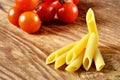 Uncooked penne pasta and cherry tomatoes