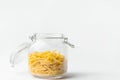 Uncooked penne pasta in glass crystal storage jar with open lid on white table wall background. Italian cuisine specialty. Kitchen Royalty Free Stock Photo
