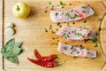 Uncooked pieces of silver carp fish with red chile pepper, bay leaf, apple, spices and garlic on wooden board, top view. Royalty Free Stock Photo