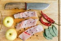 Uncooked pieces of silver carp fish with red chile pepper, bay leaf, apple, spices and knife on wooden board, top view. Royalty Free Stock Photo