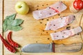 Uncooked pieces of silver carp fish with red chile pepper, bay leaf, apple, spices and knife on wooden board, top view. Royalty Free Stock Photo