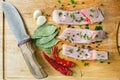 Uncooked pieces of silver carp fish with red chile pepper, bay leaf, garlic, spices and knife on wooden board, top view. Royalty Free Stock Photo