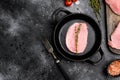 Uncooked pork chop, on frying cast iron pan, on black dark stone table background, top view flat lay, with copy space for text Royalty Free Stock Photo